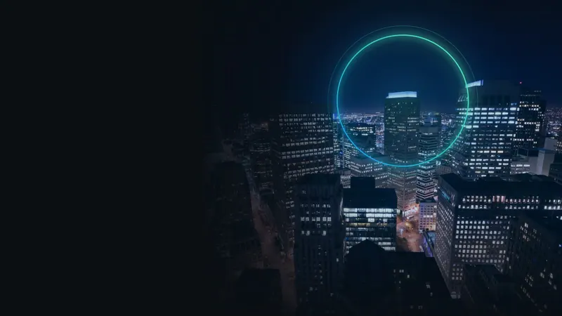 Centro comercial de uma cidade à noite, com um anel de luz azul e verde-água em volta das torres